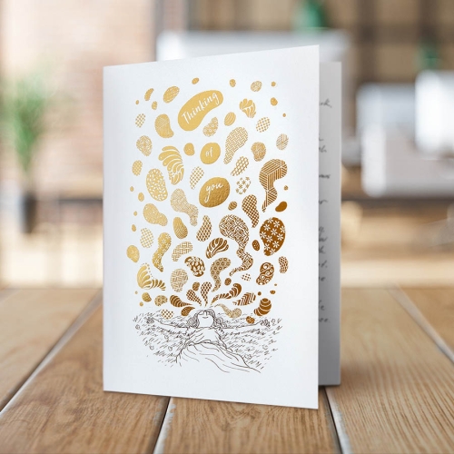 greeting cards with matching illustrated envelopes featuring gold foil. This card is shown standing on a desk next to a plant